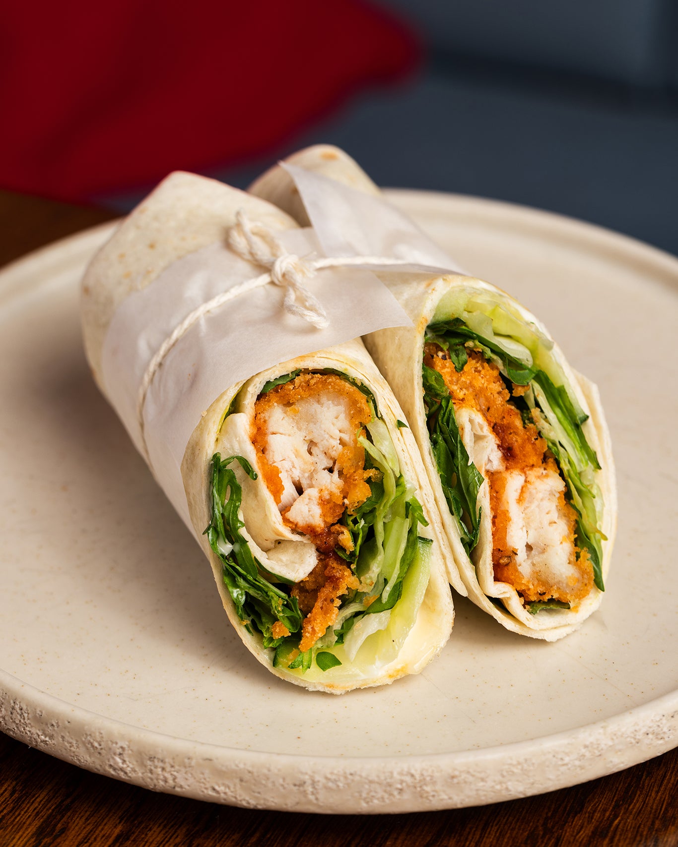 Wrap with chicken and lettuce on a beige plate