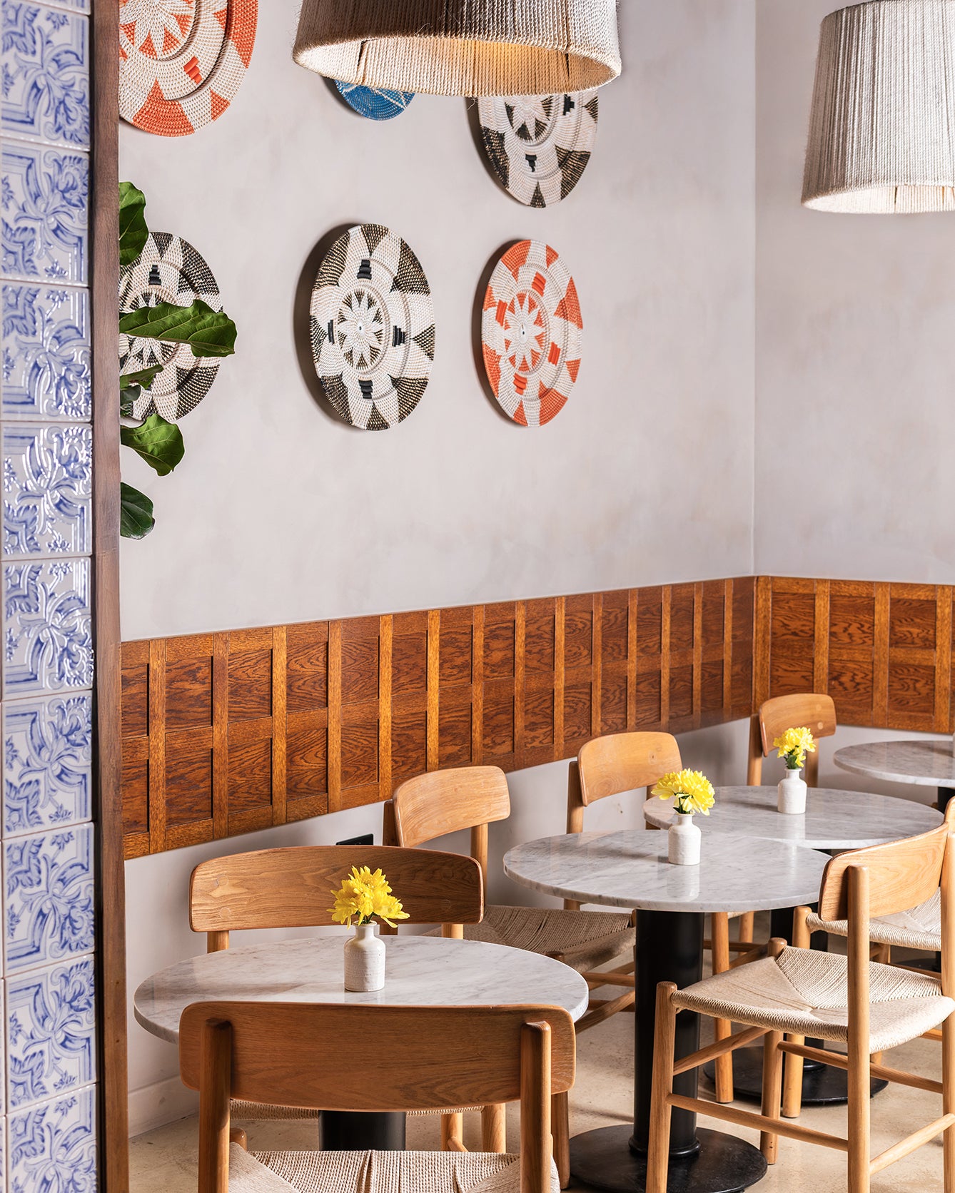 Modern restaurant interior with wooden chairs, tables, and decorative wall art.